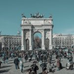 A bustling scene at Arco della Pace in Milan, capturing diverse people under a clear sky. — Coronavirus disease 2019