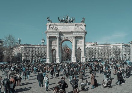 A bustling scene at Arco della Pace in Milan, capturing diverse people under a clear sky. — Coronavirus disease 2019