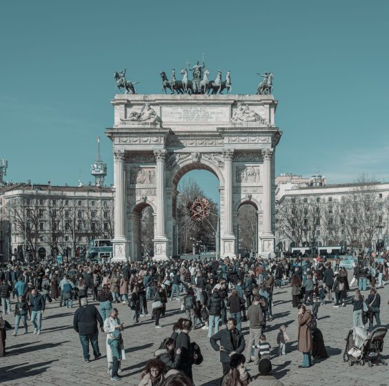A bustling scene at Arco della Pace in Milan, capturing diverse people under a clear sky. — Coronavirus disease 2019