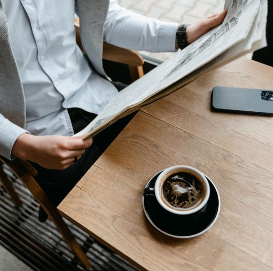 An adult male enjoying his coffee while reading a newspaper at a cafe with his smartphone nearby. — Le profil complet de Loco