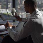 Businessman in office reading sports section, enjoying coffee with city view. — Quelles sont les limites de mise au Magical S