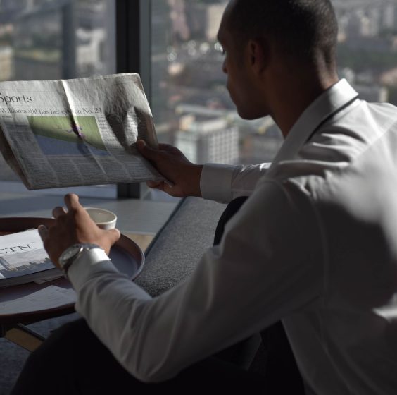 Businessman in office reading sports section, enjoying coffee with city view. — Quelles sont les limites de mise au Magical S