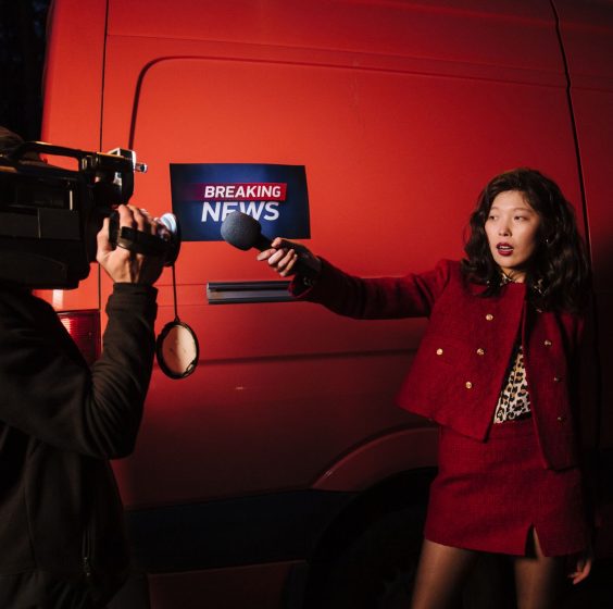 Asian female reporter with cameraman conducting a nighttime news broadcast beside a news van. — Wie schnell sind die Auszahlu